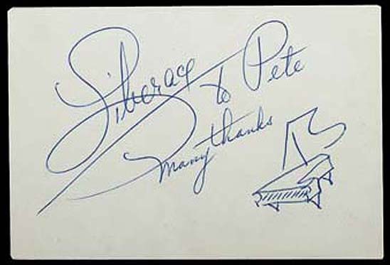 A card signed by Liberace with his distinctive signature and grand piano sketch