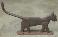 A cast iron boot scraper, unattributed, in the form of a cat with [long tail and] traces of black paint.