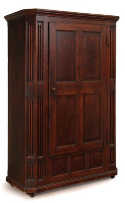 Furniture: A carved schrank, Zoar, Tuscarawas County, Ohio, mid 19th century, cherry, walnut, and poplar. One-piece [wardrobe],with [molded cornice], canted and carved pilasters, paneled door, and diamond panels below the door. Interior with carved hooks and a shelf.